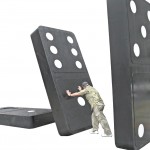 Man pushing over a huge domino