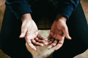 Man holds his hands open in prayer